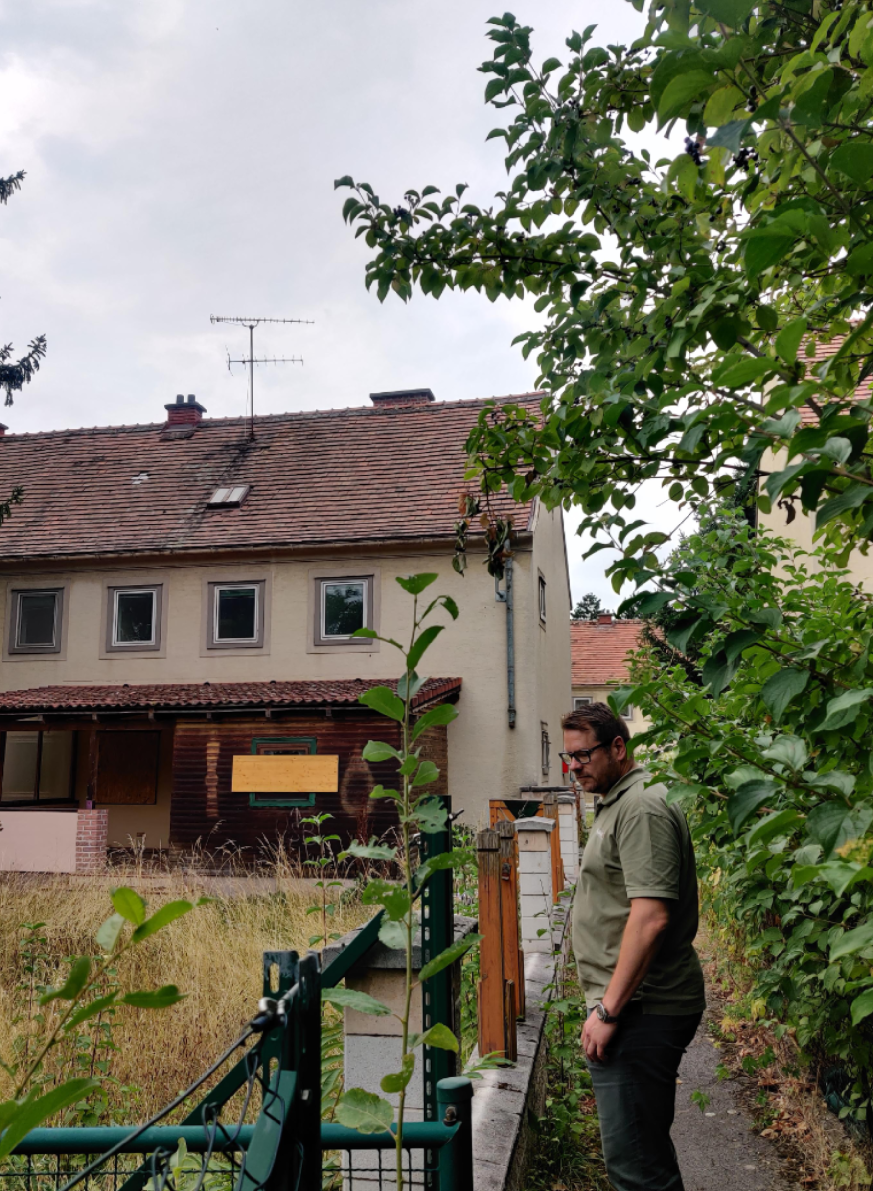 Hinterseite der Altbauten, davor ein verwilderter Garten